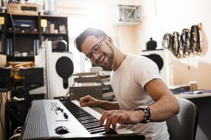 Young passionate man playing electric piano