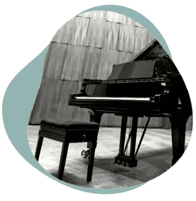 Black grand piano and bench on an empty concert stage